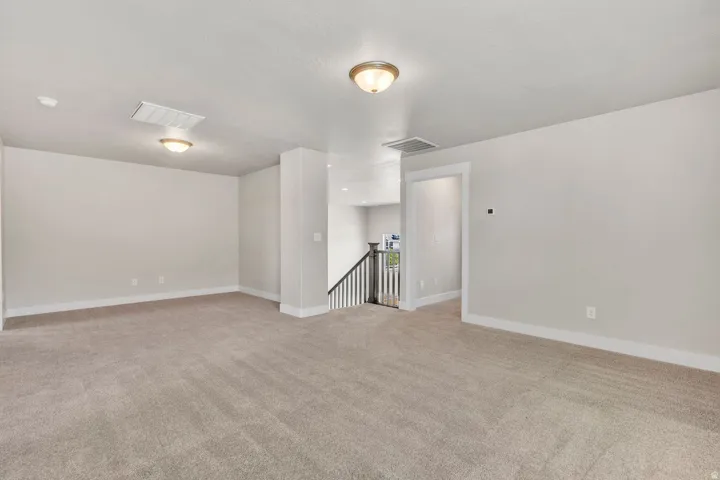 Carpeted loft area featuring neutral wall tones, baseboard trim, and two flush-mount ceiling light fixtures