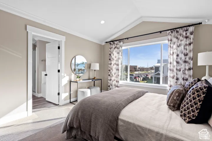 Sophisticated primary bedroom showcasing expansive windows with cityscape panorama, neutral designer palette with taupe walls and white trim, hardwood-finish flooring, and a spa-like ensuite featuring a circular mirror and contemporary vanity