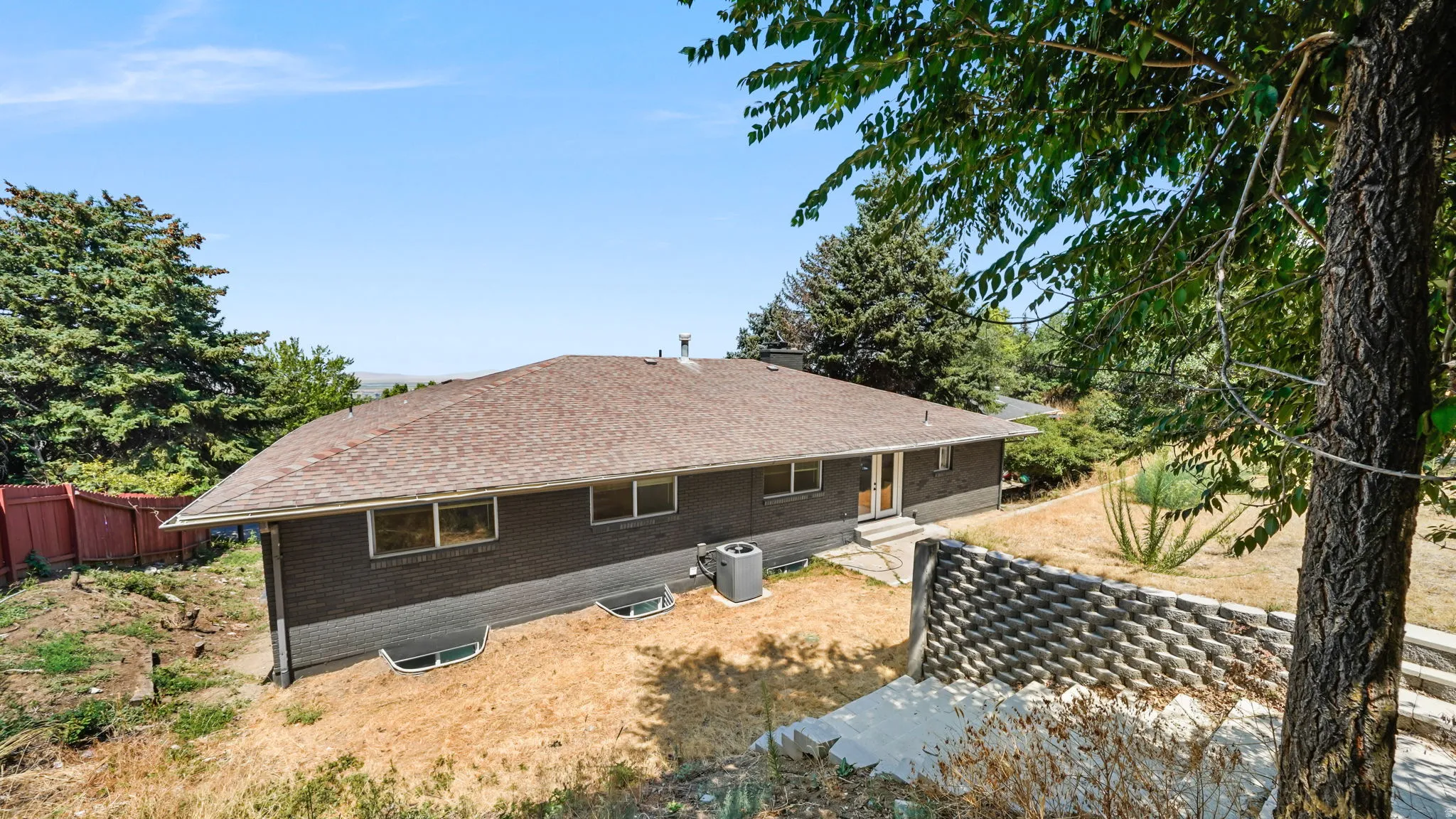 Modern ranch-style residence featuring a low-pitched composition shingle roof, horizontal wood-finish siding in a charcoal tone, and multiple casement windows across the façade