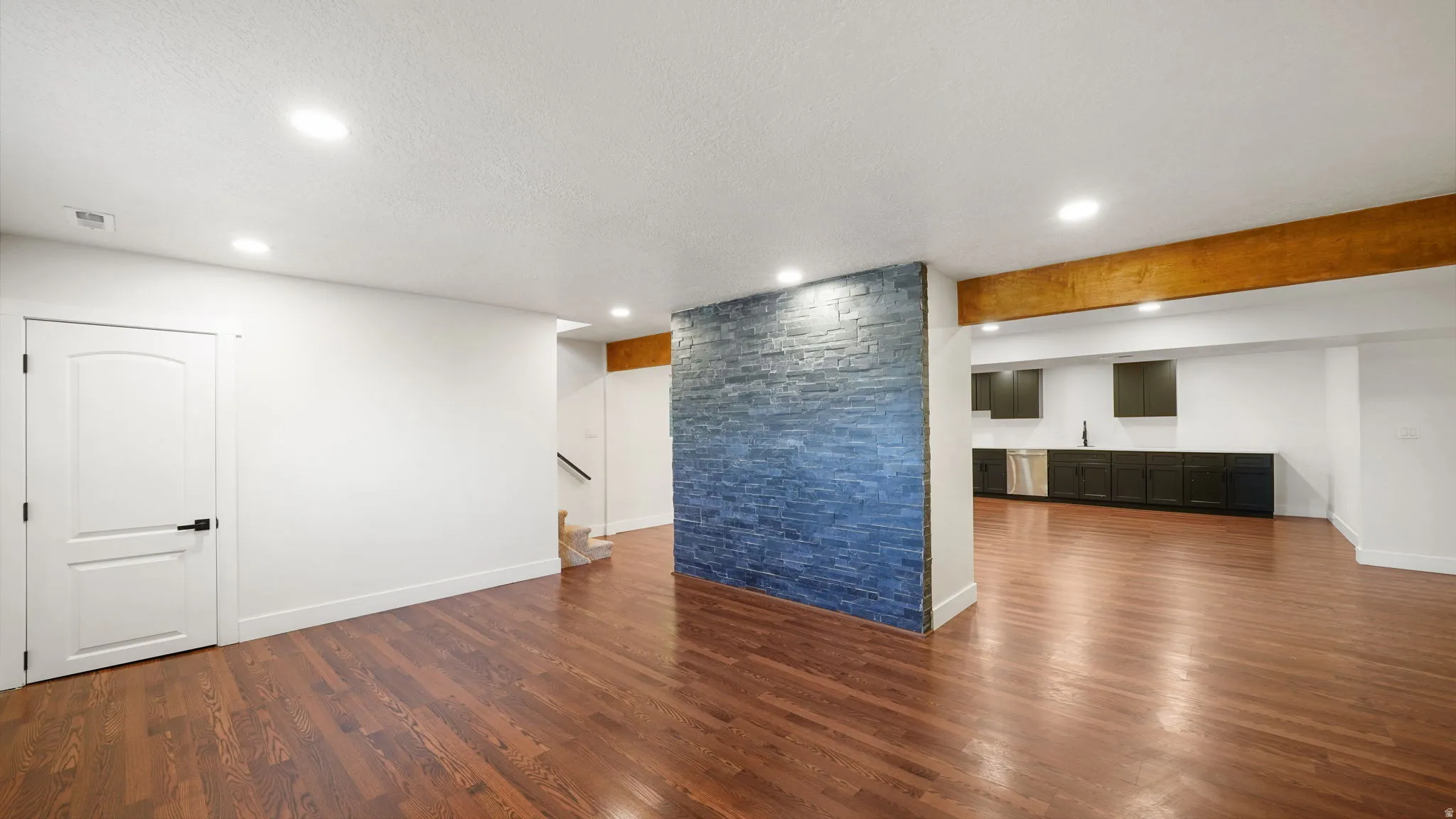 Expansive open-concept space featuring rich wood-finish flooring throughout, recessed lighting, and soaring exposed wood beam ceilings