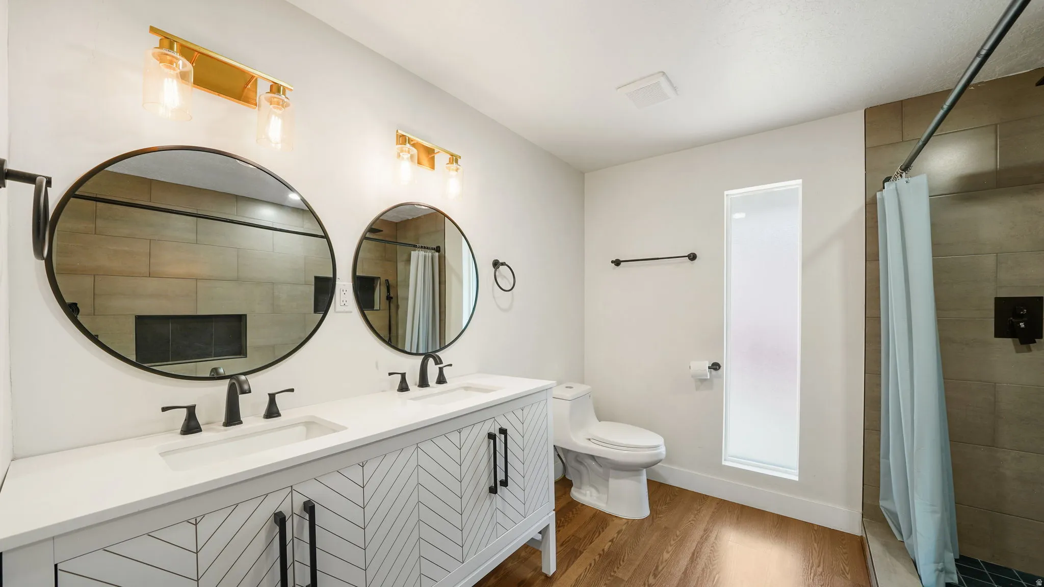 Dual vanity with white countertops and herringbone-patterned cabinetry