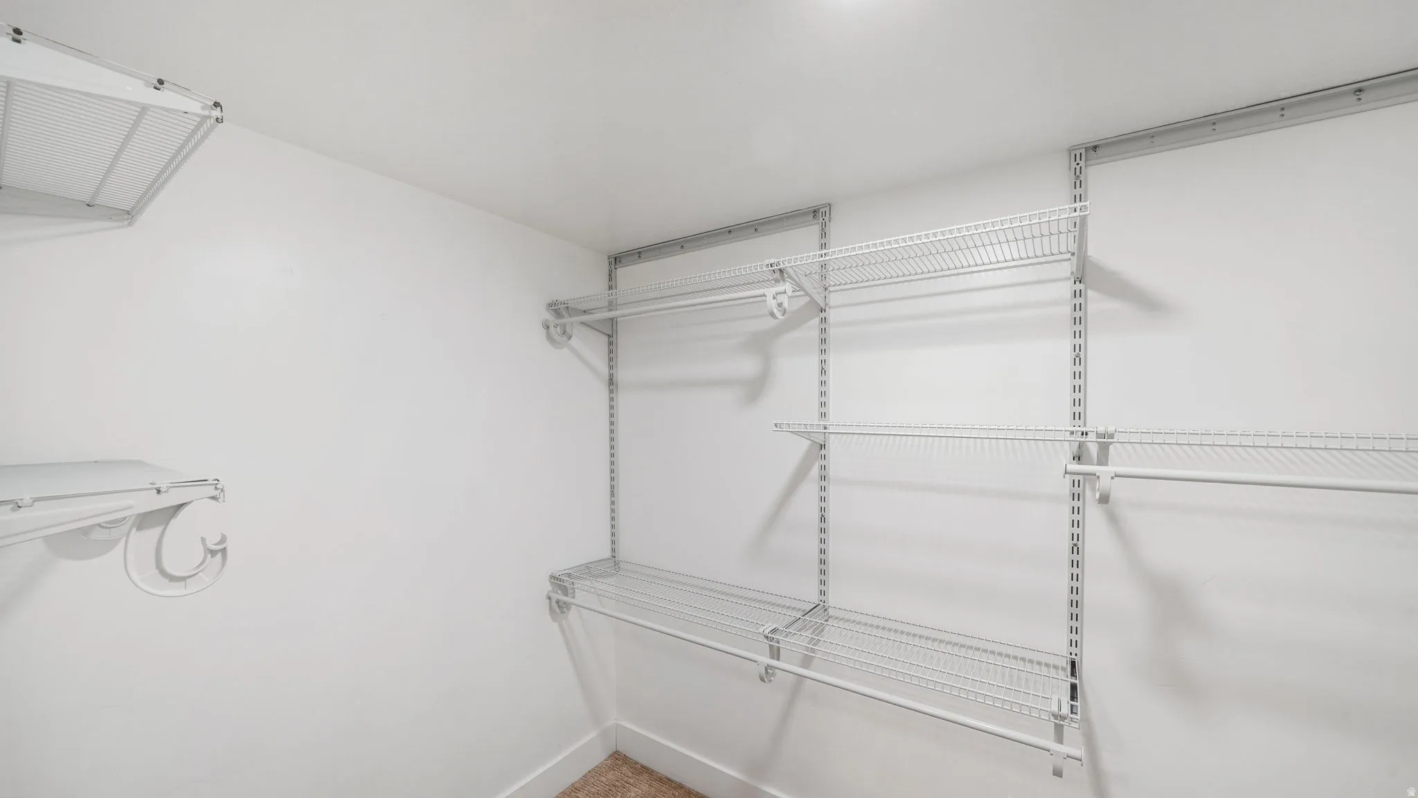 Spacious walk-in closet featuring wall-mounted wire shelving with multiple tiers, chrome hardware, and wooden flooring