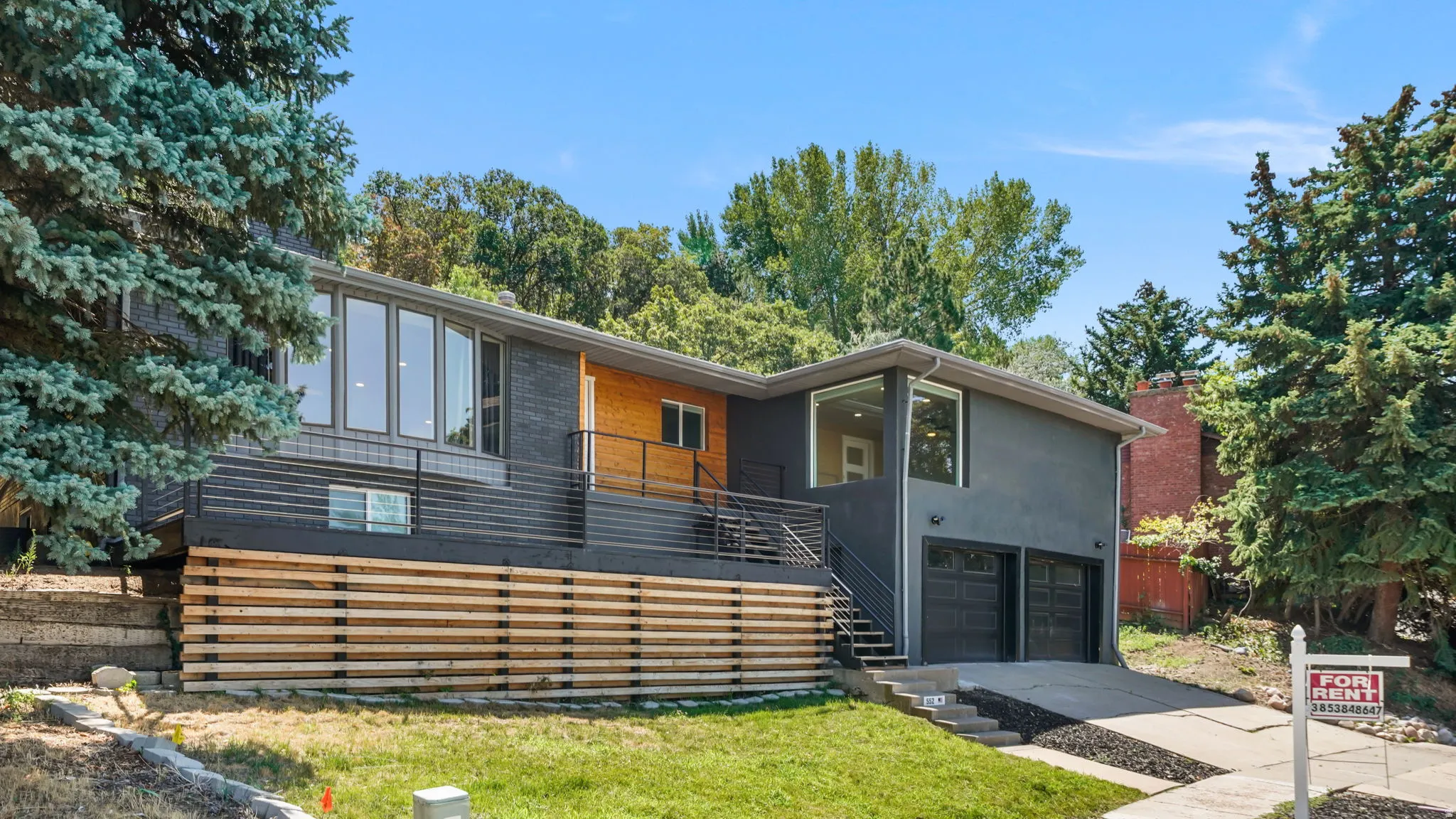 Modern architectural design featuring a striking mixed-material exterior with horizontal wood-finish siding, charcoal cladding, and warm-toned accent paneling