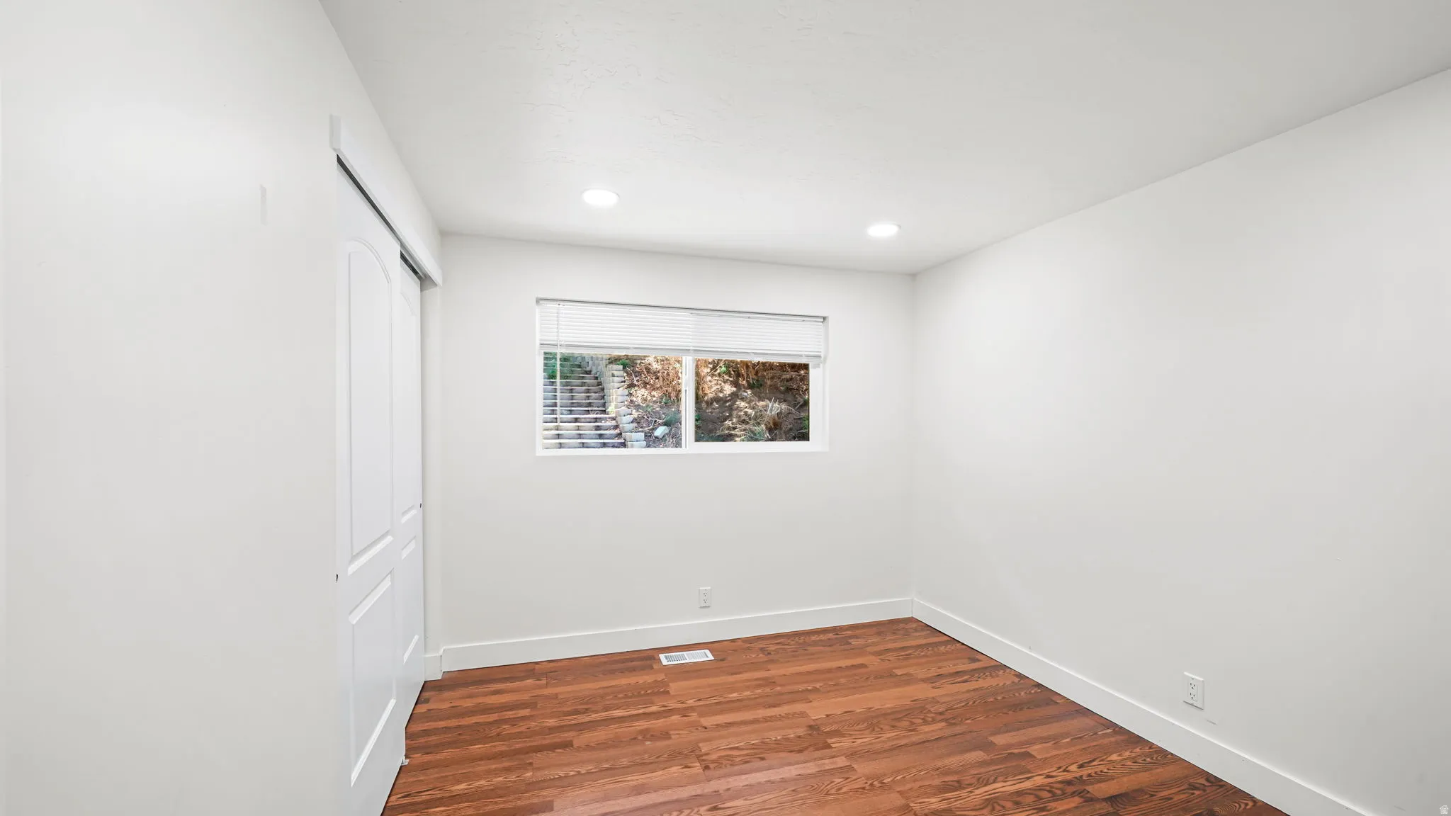 Bright interior space featuring wood-finish flooring, recessed lighting, and a window with blinds