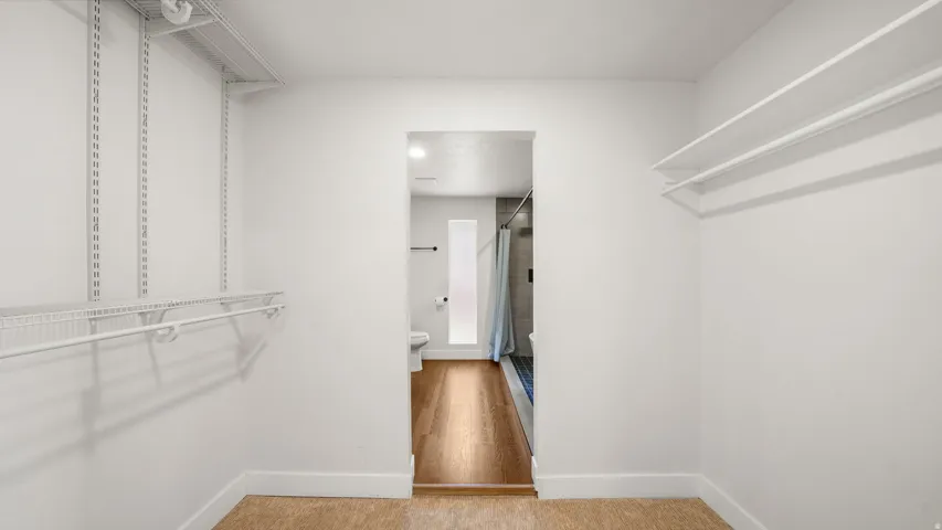 Spacious walk-in closet featuring white wire shelving, polished chrome hanging rods, wood-finish flooring, and recessed ceiling lighting