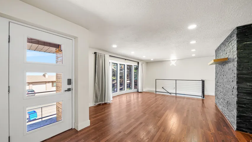 Entryway featuring a modern door with multiple glass panes, opening to a spacious room with wood-finish flooring