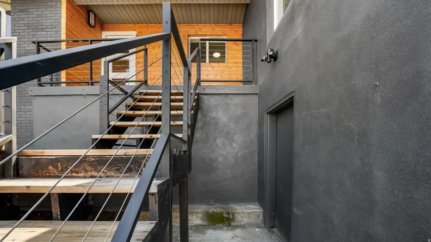 Modern industrial staircase featuring steel cable railings, open-tread metal steps, and a sleek black steel frame