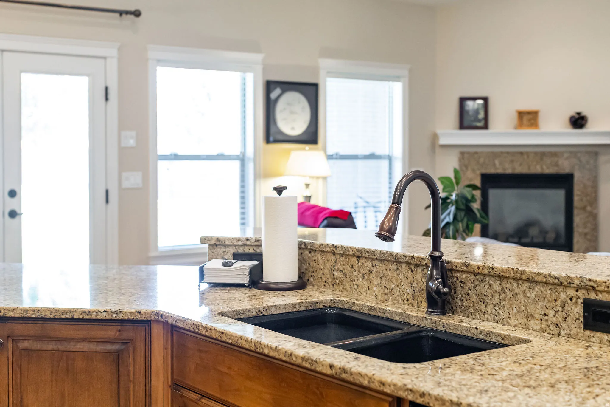 Kitchen island featuring granite countertops, a dark-finish double basin sink, and a bronze-toned pull-down faucet