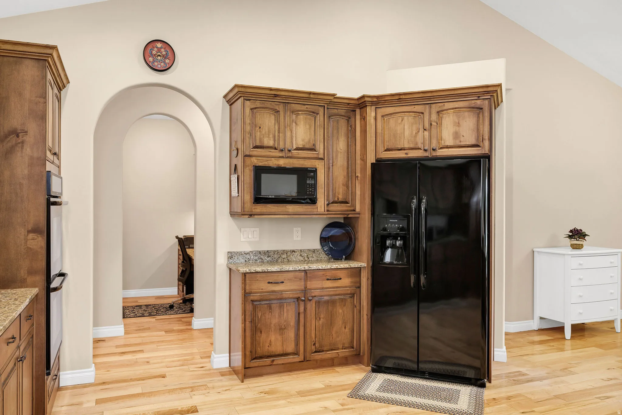 Open-concept kitchen and dining area featuring warm wood-finish cabinetry, stainless steel appliances, granite countertops, and recessed lighting
