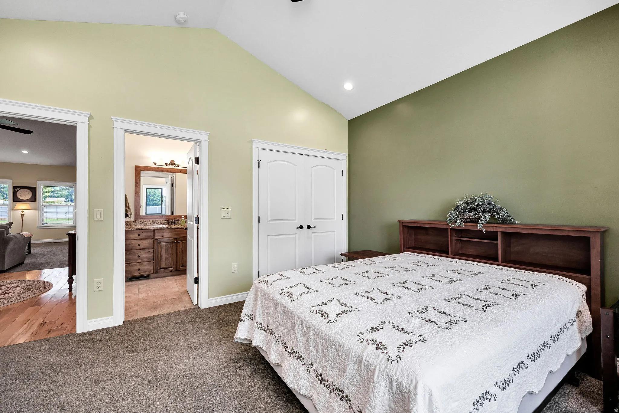 Spacious primary bedroom featuring a wood-finish bed frame, carpeted flooring, and dual-tone wall finishes in soft yellow and sage green