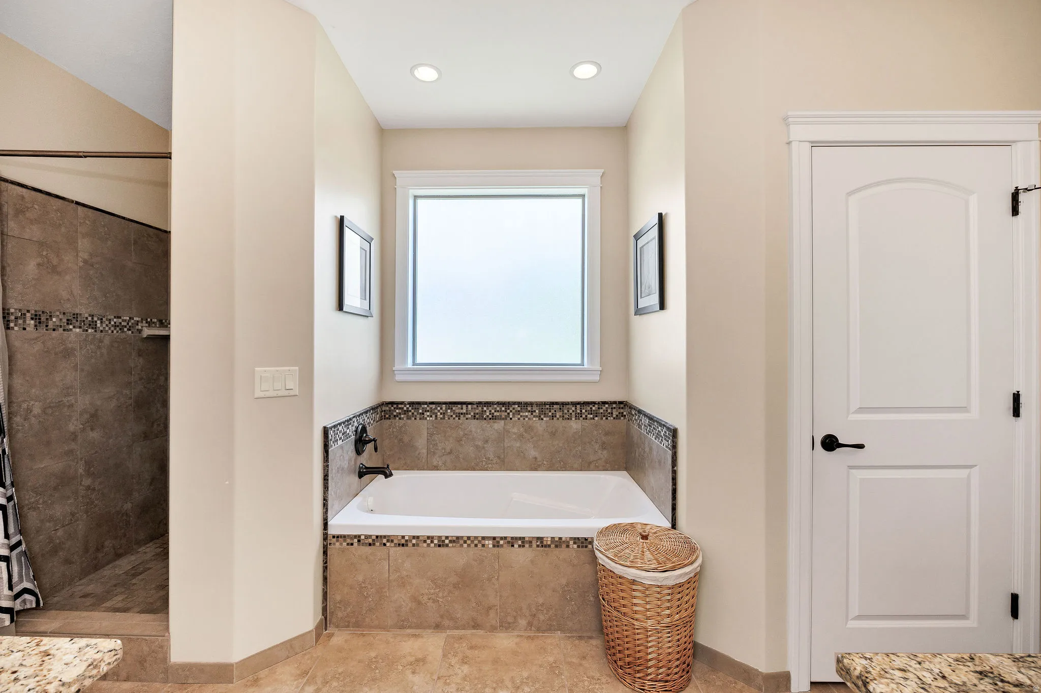 Bathroom featuring a built-in tub with tile surround and mosaic accent, a separate walk-in shower with full tile, and a privacy window