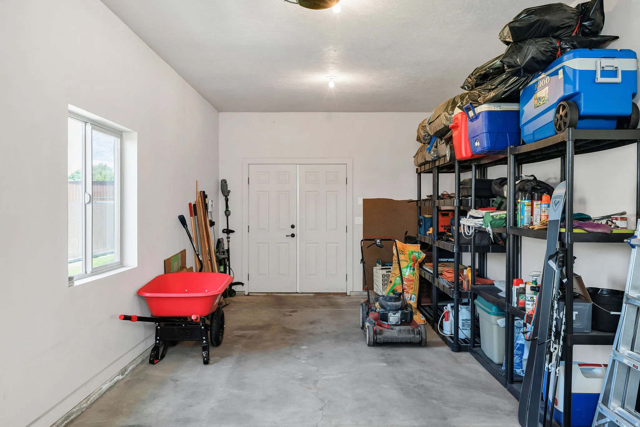 Concrete flooring in a garage space featuring a double-door entry and a single window