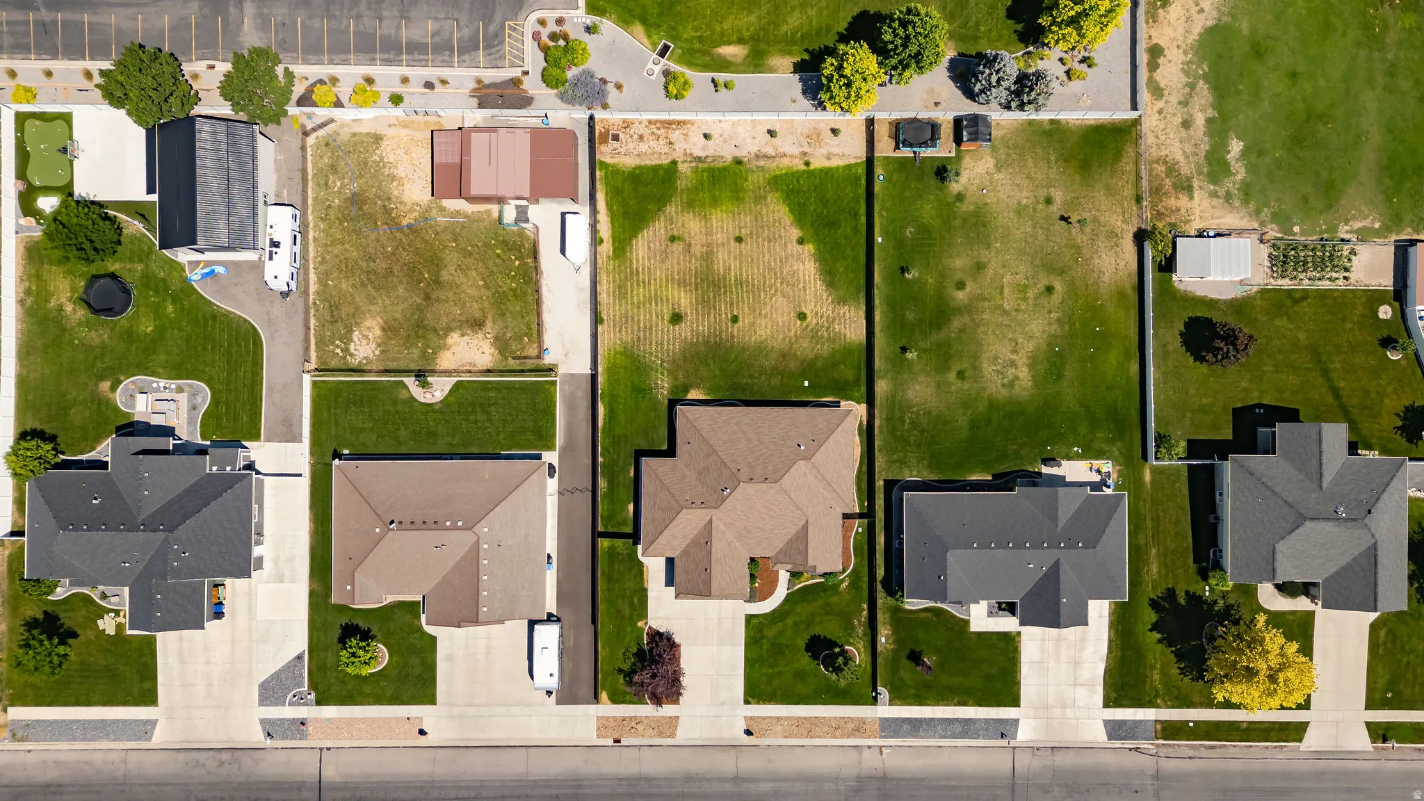 Aerial view showcasing five well-proportioned residential properties with individual driveways, mature landscaping, and expansive lawns