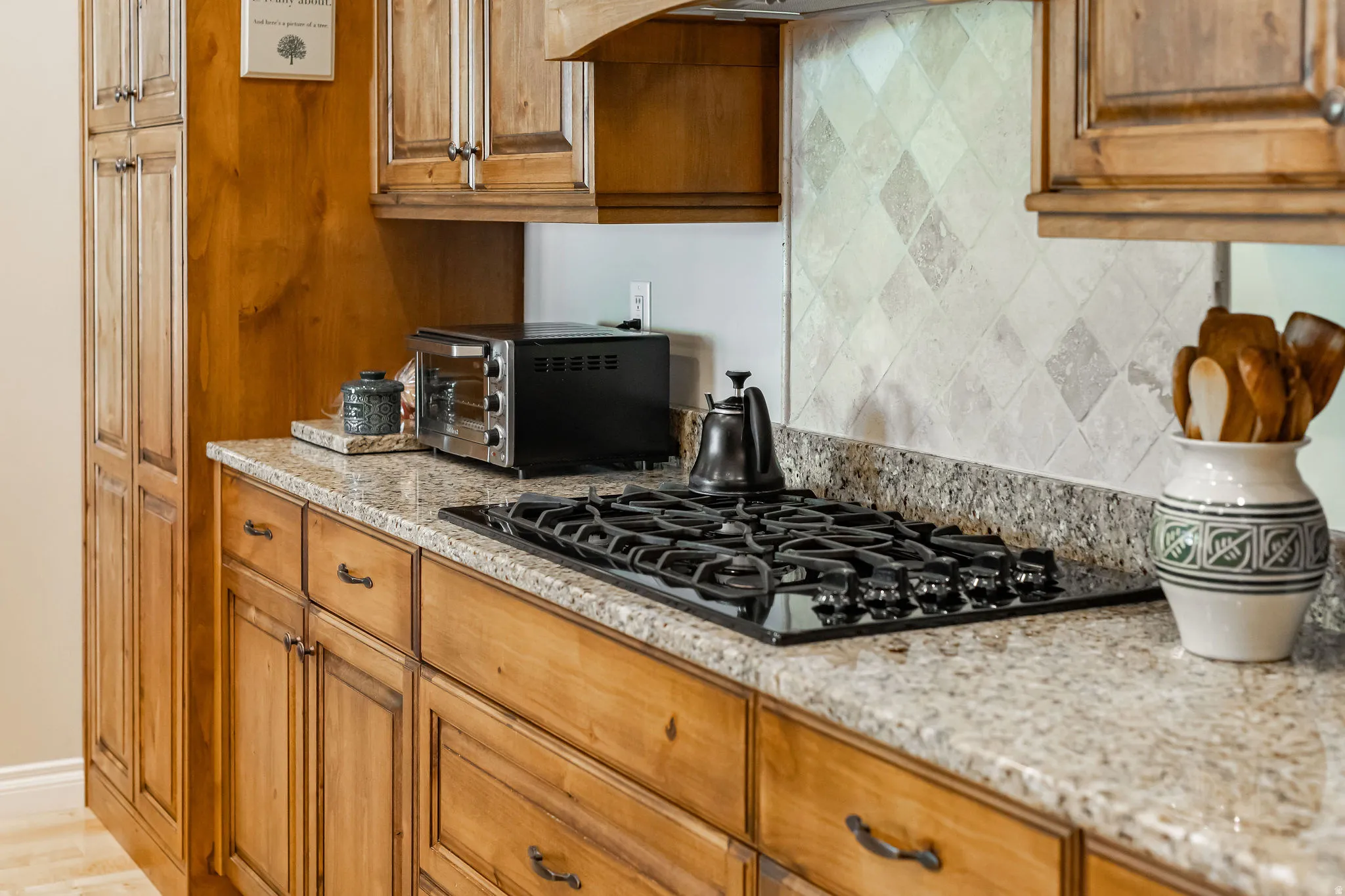 Chef's kitchen showcasing custom wood cabinetry with bronze hardware, granite countertops, and a professional-grade gas cooktop