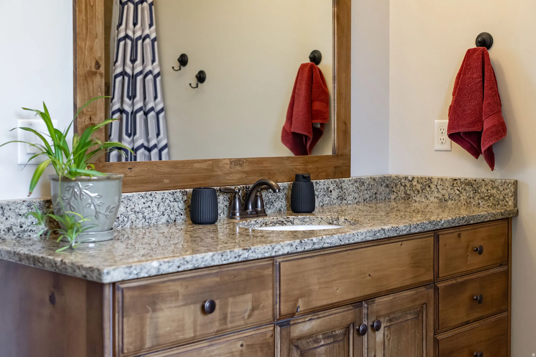 Wood-finish vanity with an integrated white sink, stone-look countertop, and a framed mirror