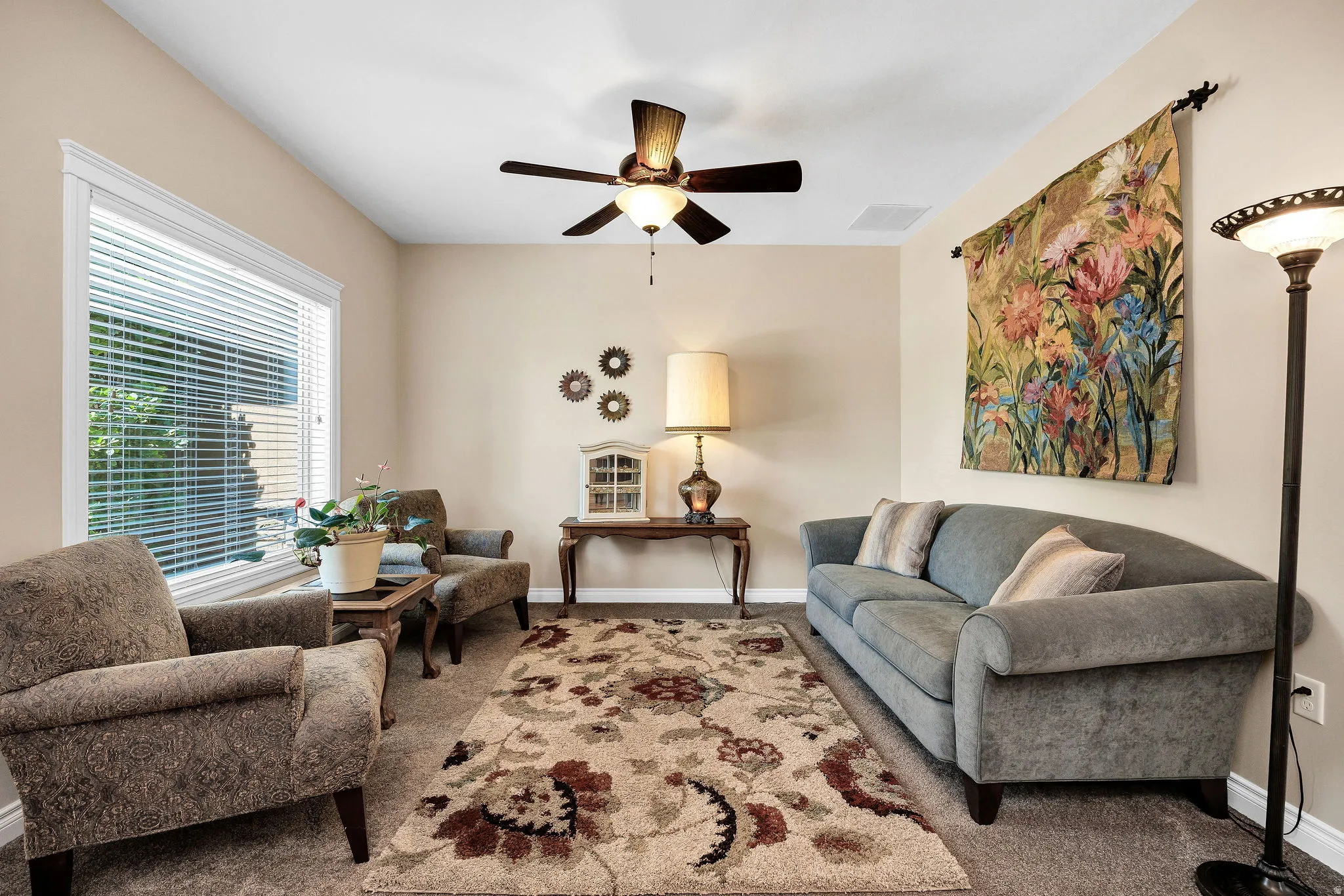 Elegant living room showcasing a gray upholstered sofa, complementary accent chair, and ceiling fan with brass accents