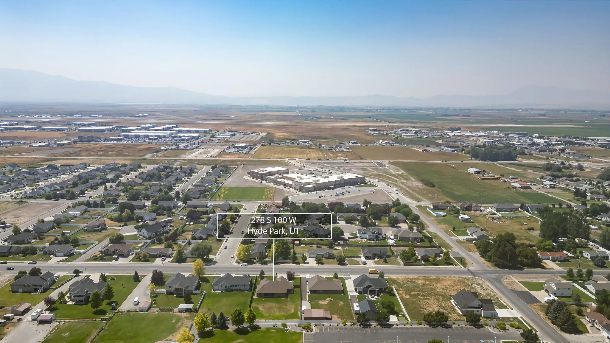 Aerial perspective showcasing a residential neighborhood with surrounding developed areas and distant mountains