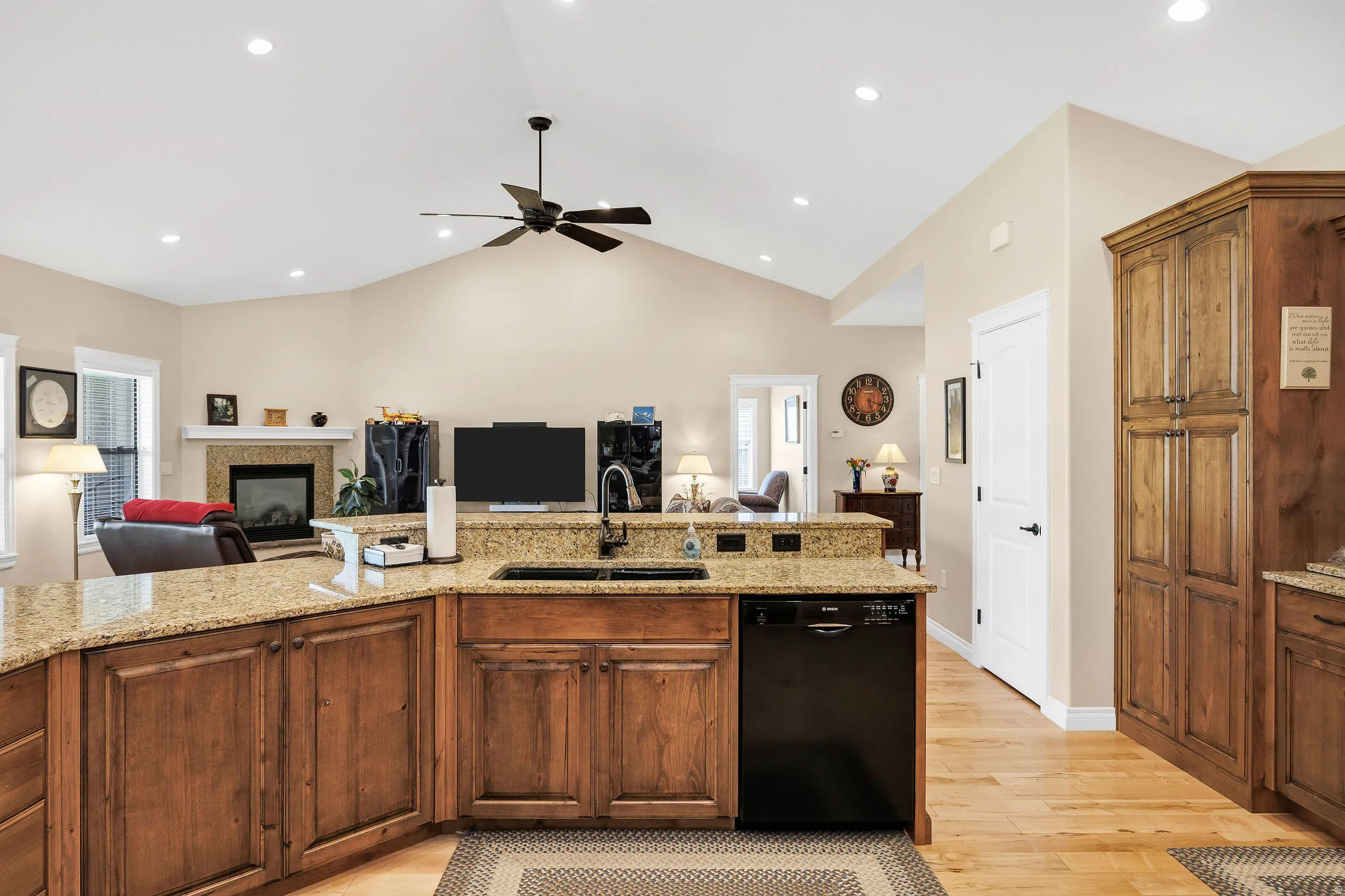 Kitchen featuring an island with granite countertops, wood-finish cabinetry, and a black dishwasher