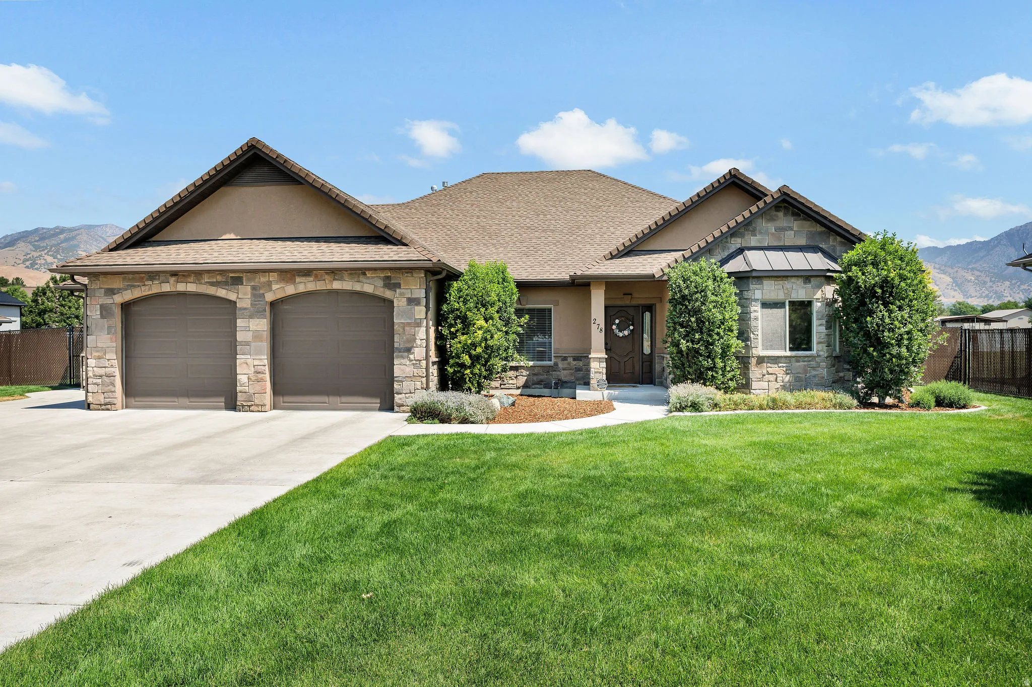 Stunning single-story residence showcasing a stone and stucco exterior with a prominent two-car garage