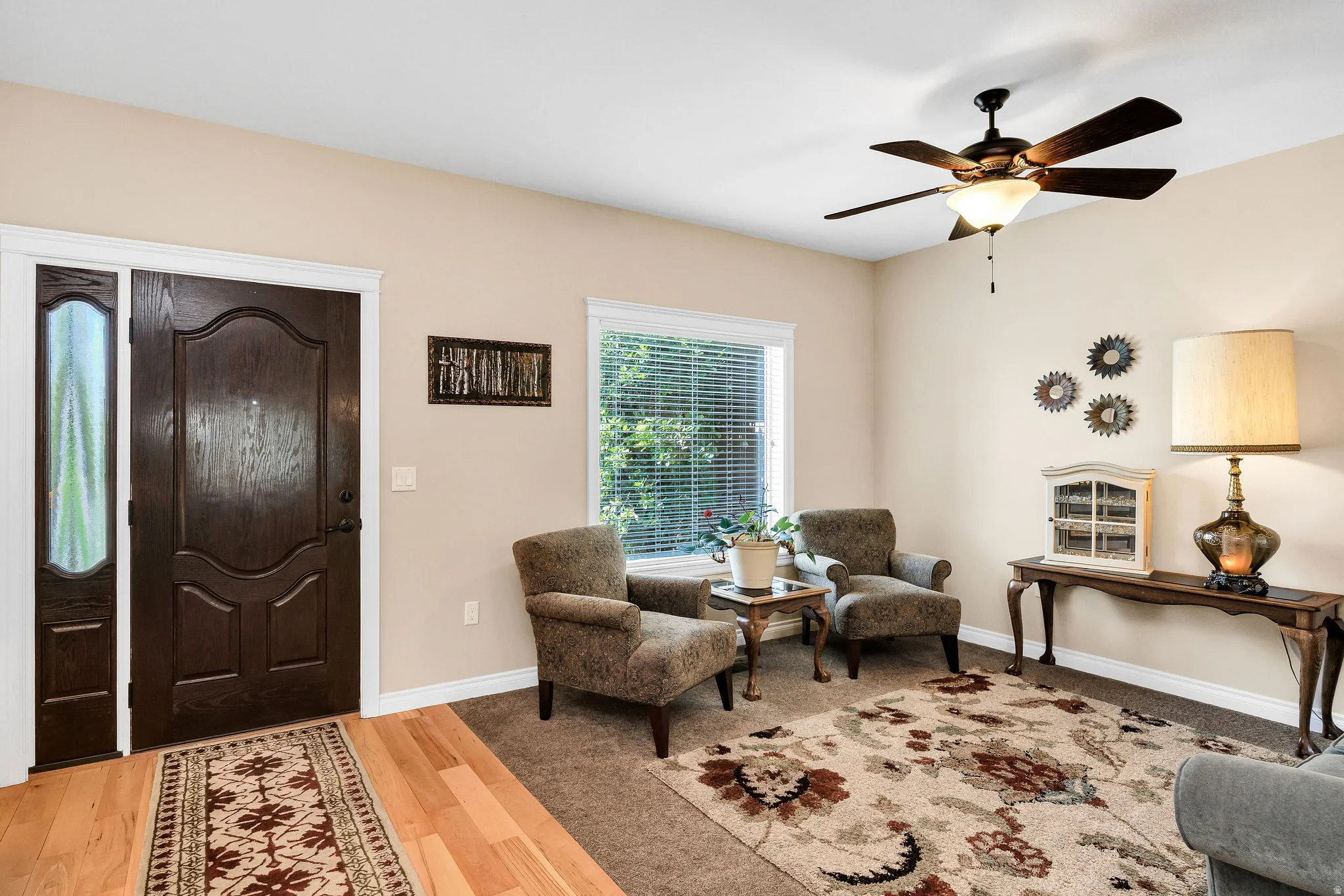 Welcoming foyer and living area featuring hardwood flooring, a decorative area rug, and neutral wall finishes