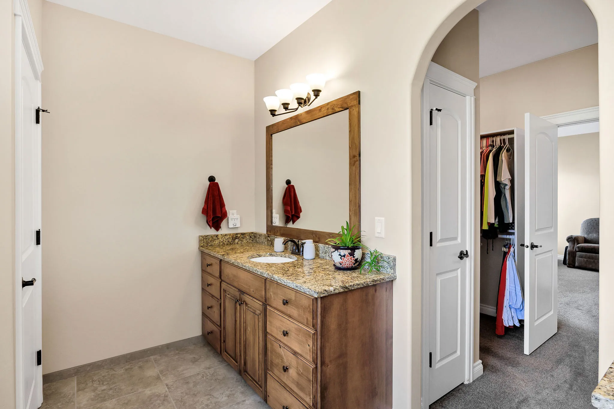 Dual-sink vanity featuring wood-finish cabinetry with multiple drawers, granite countertop, and integrated lighting