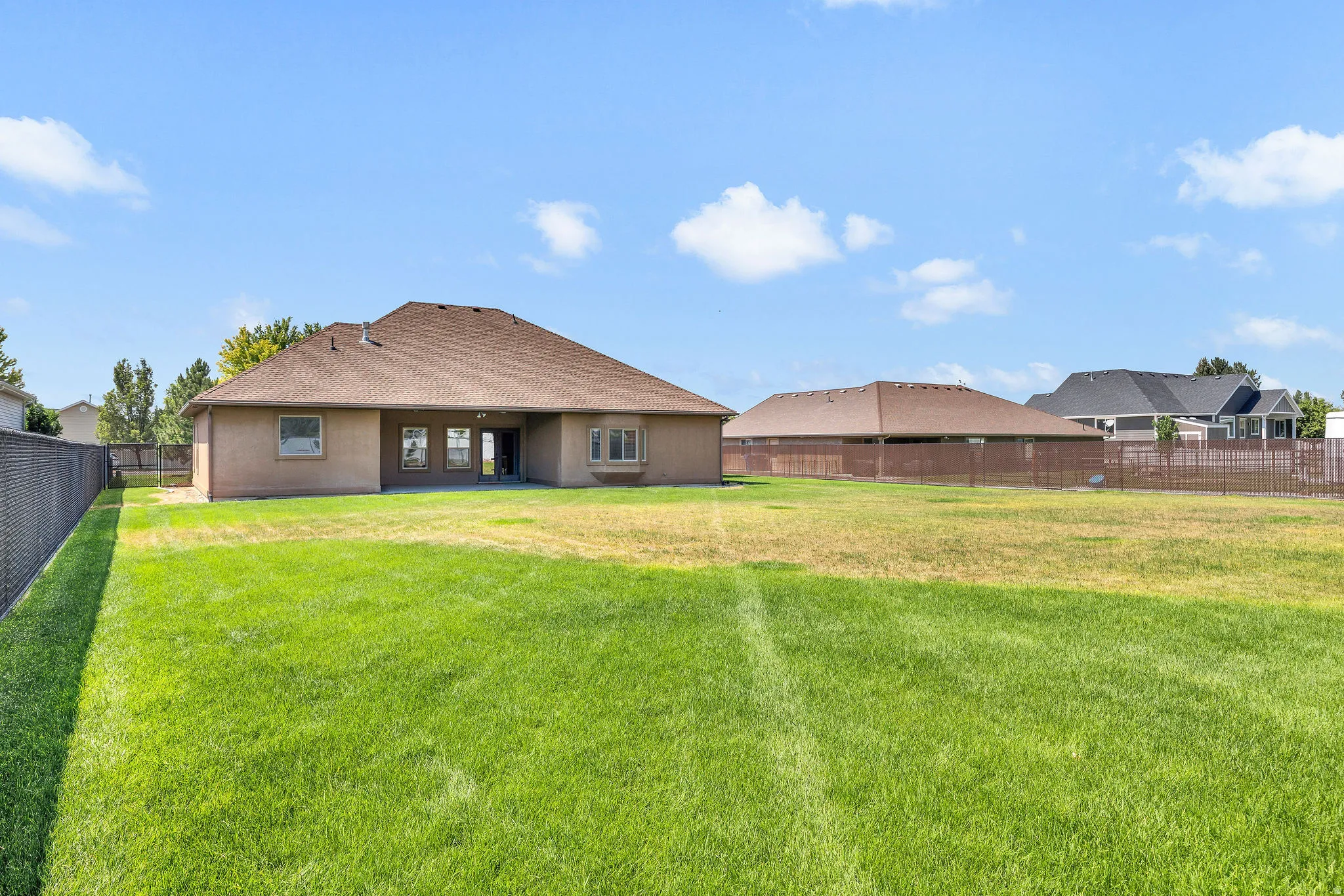 Expansive rear yard featuring a large grass area and secure chain-link fencing