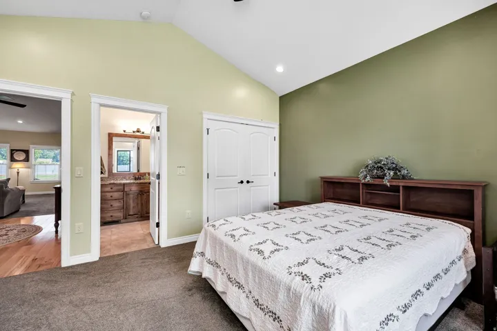 Spacious primary bedroom featuring a wood-finish bed frame, carpeted flooring, and dual-tone wall finishes in soft yellow and sage green