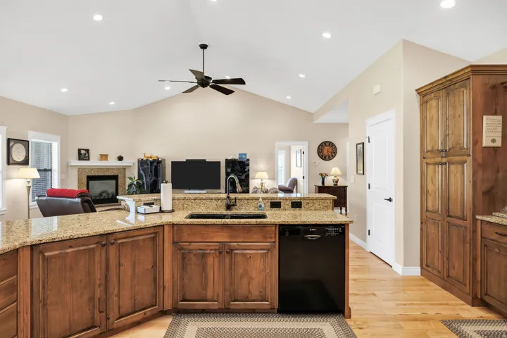 Kitchen featuring an island with granite countertops, wood-finish cabinetry, and a black dishwasher