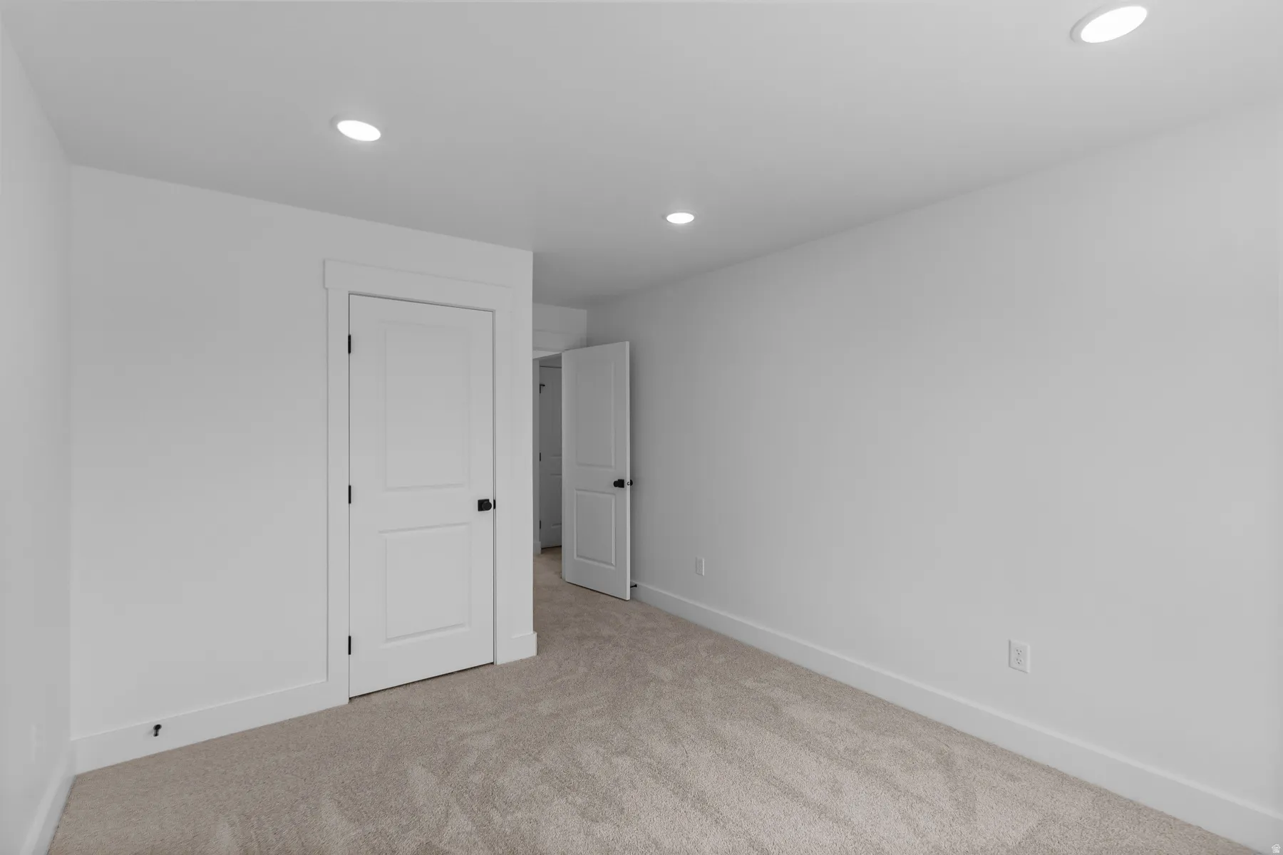 Spacious bedroom featuring recessed ceiling lighting, neutral wall finishes, and soft carpeting throughout