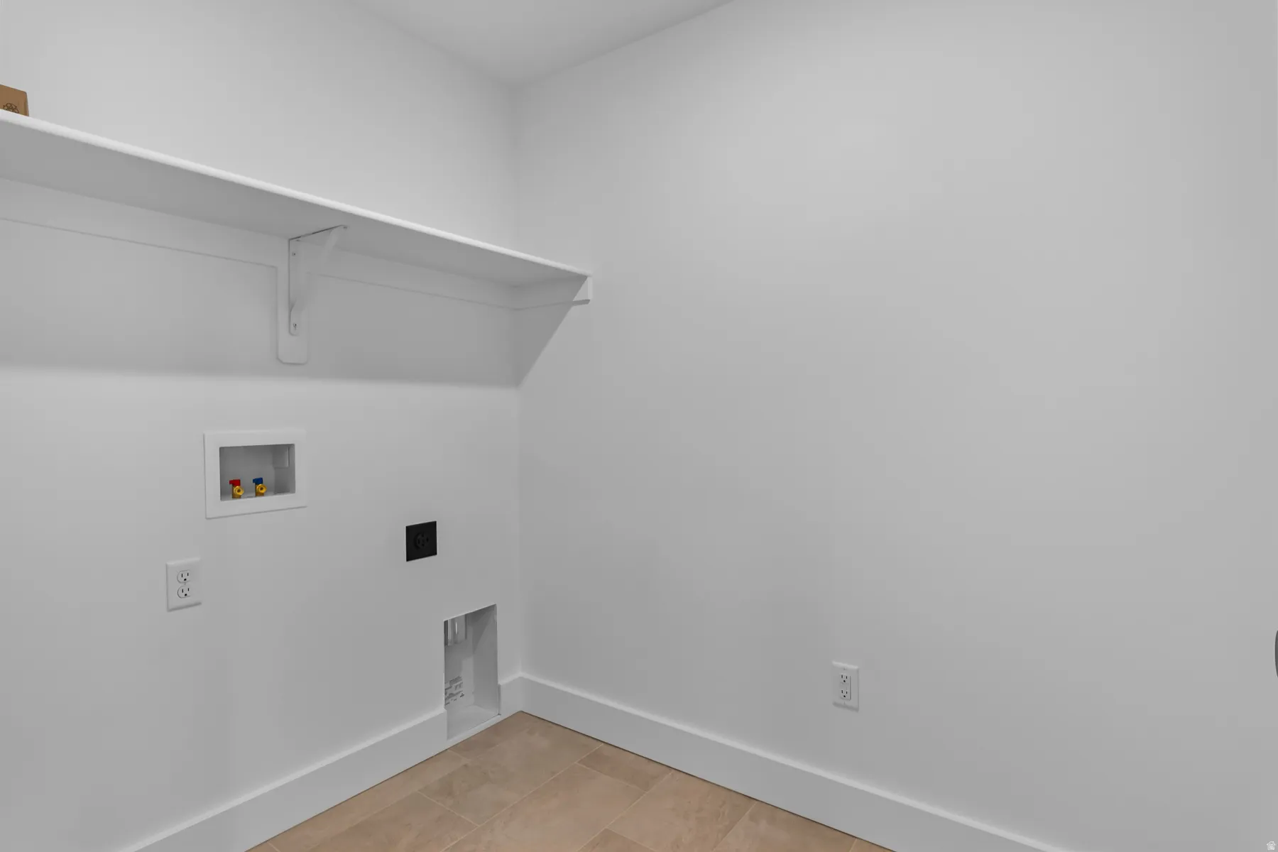 Laundry room featuring a white wall shelf, utility hookups, and light-toned tile flooring