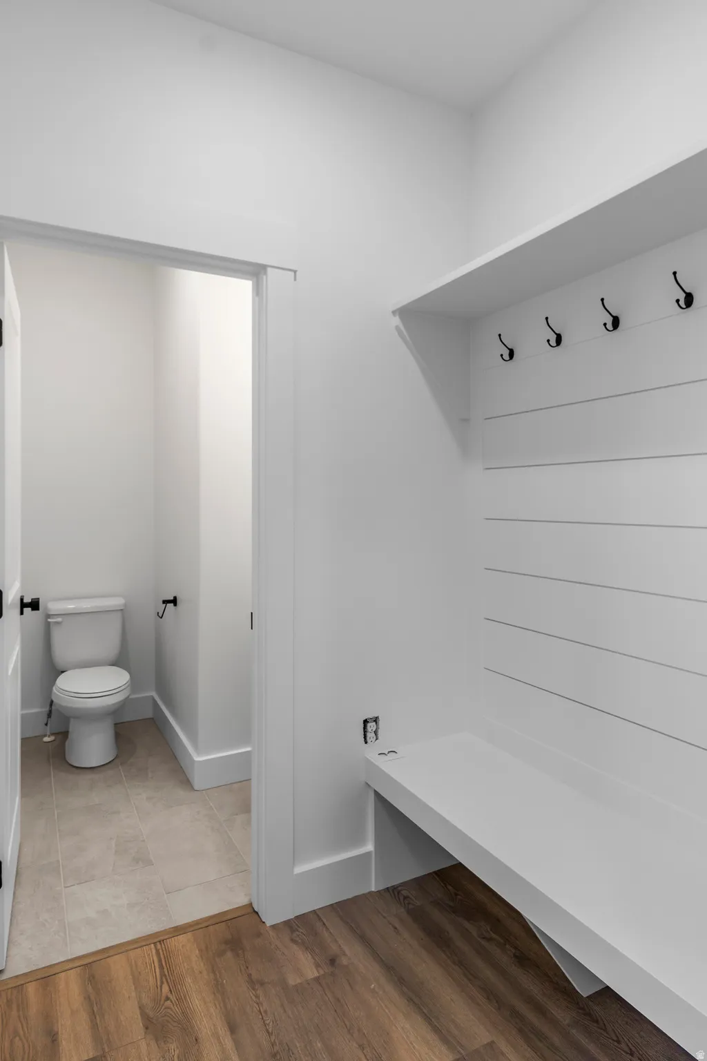 Entryway featuring wood-finish flooring, a built-in bench, and coat hooks