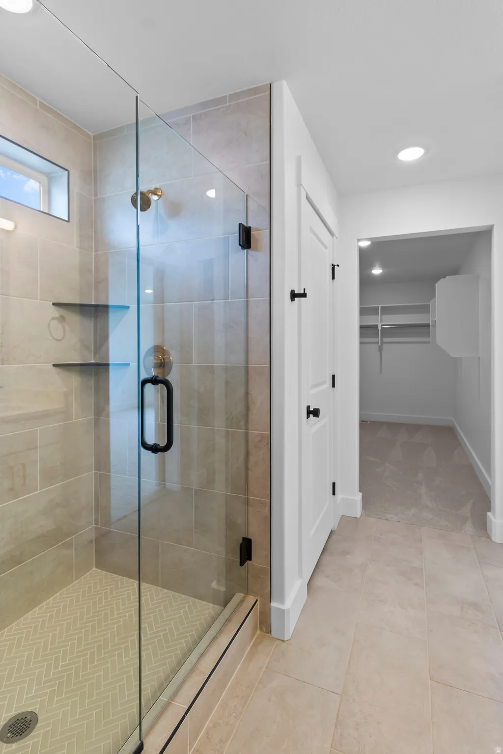 Spa-inspired primary bathroom suite featuring a frameless glass-enclosed shower with premium tilework, dual showerheads, and integrated shelving