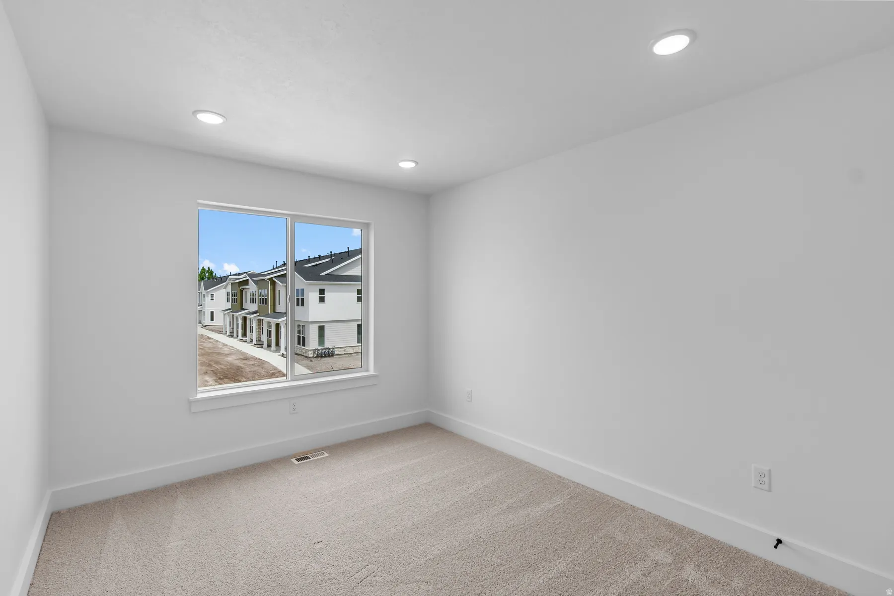 Bright secondary bedroom featuring large dual-pane windows with expansive natural light, neutral wall finishes, carpet flooring, and recessed ceiling lighting