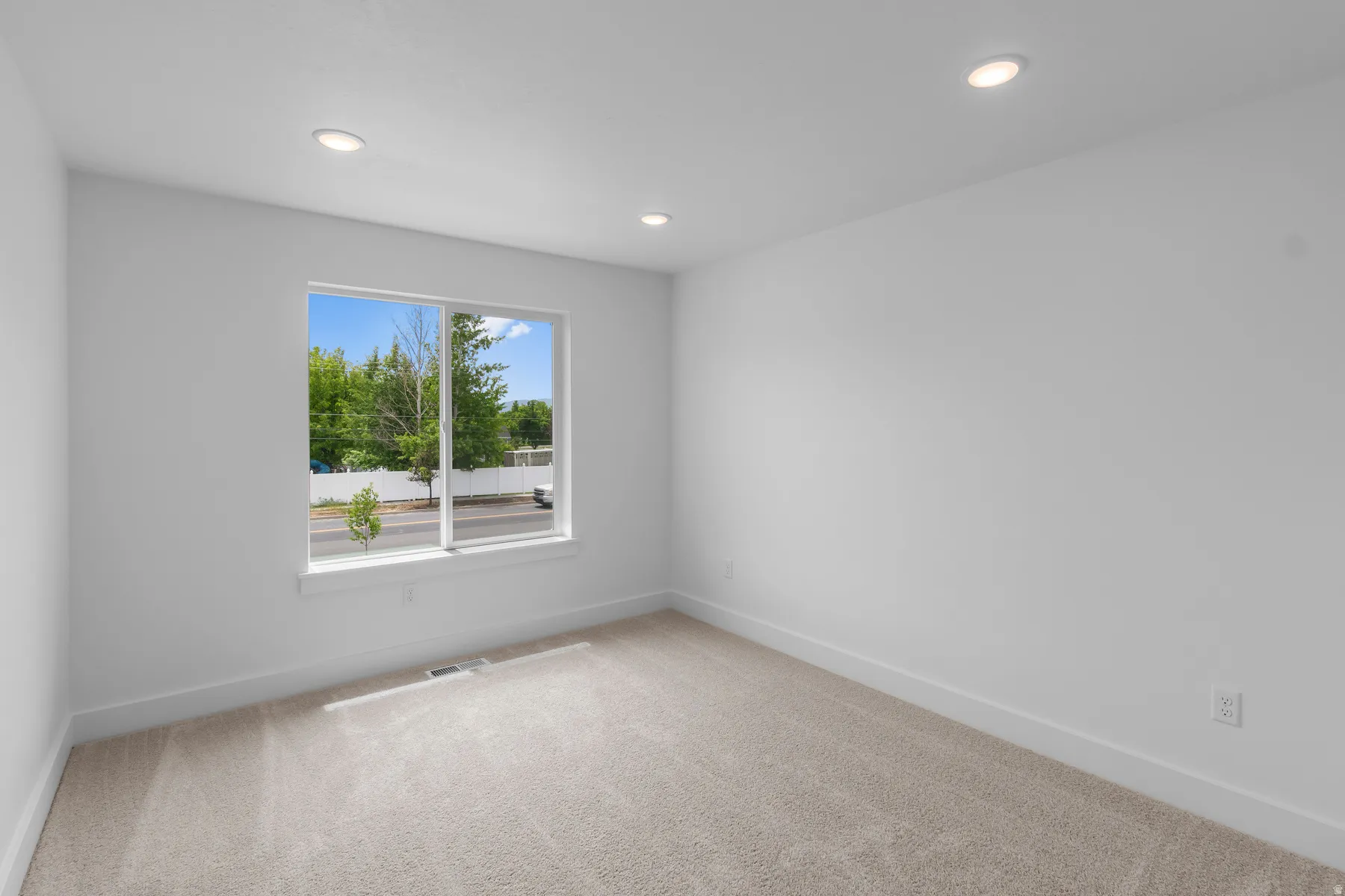 Bright and airy bedroom featuring large dual-pane windows with expansive natural light, recessed ceiling lighting, neutral wall finishes, and soft carpet flooring