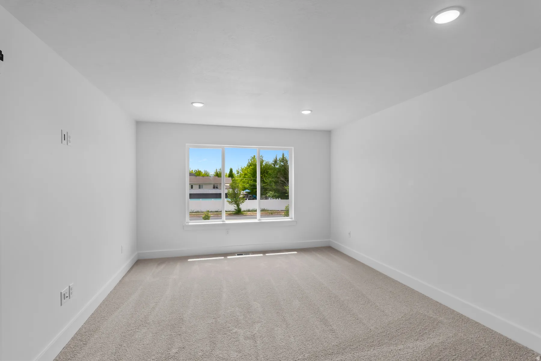 Bright secondary bedroom featuring recessed ceiling lighting, neutral wall finishes, and warm wood-finish flooring