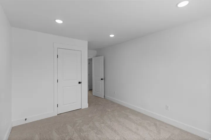 Spacious bedroom featuring recessed ceiling lighting, neutral wall finishes, and soft carpeting throughout