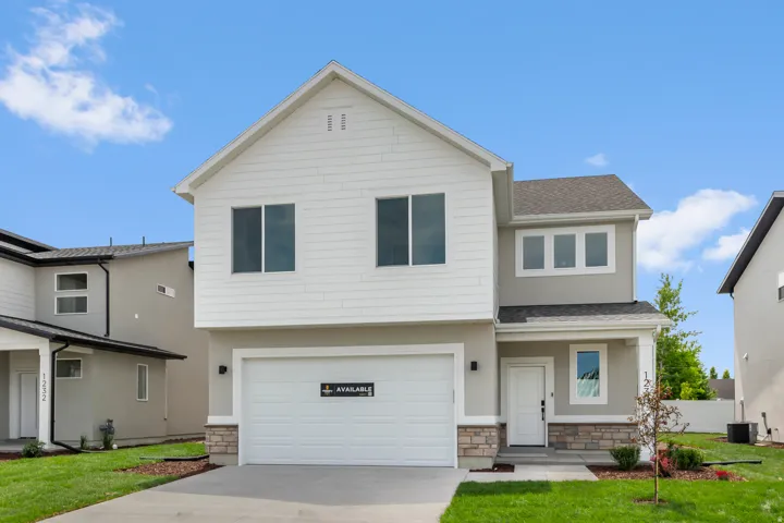 Modern two-story home featuring a clean white exterior with stone accents, two-car garage with contemporary paneling, and a gabled roofline