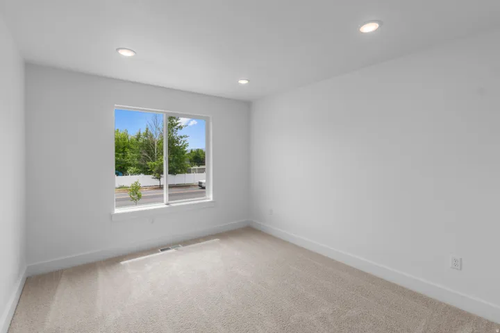 Bright and airy bedroom featuring large dual-pane windows with expansive natural light, recessed ceiling lighting, neutral wall finishes, and soft carpet flooring