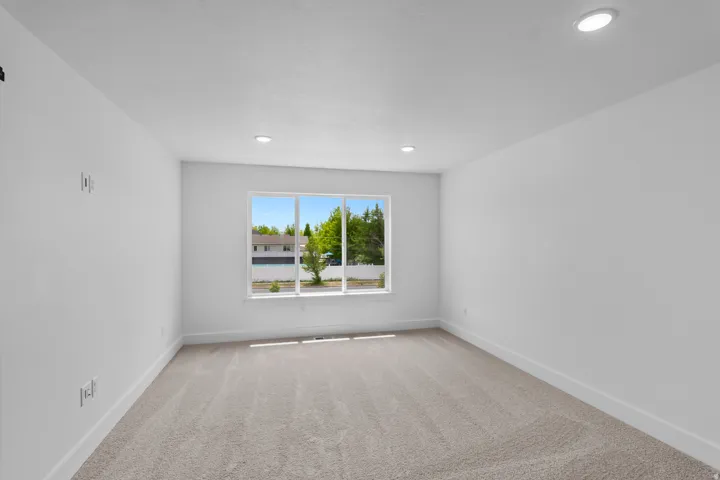 Bright secondary bedroom featuring recessed ceiling lighting, neutral wall finishes, and warm wood-finish flooring