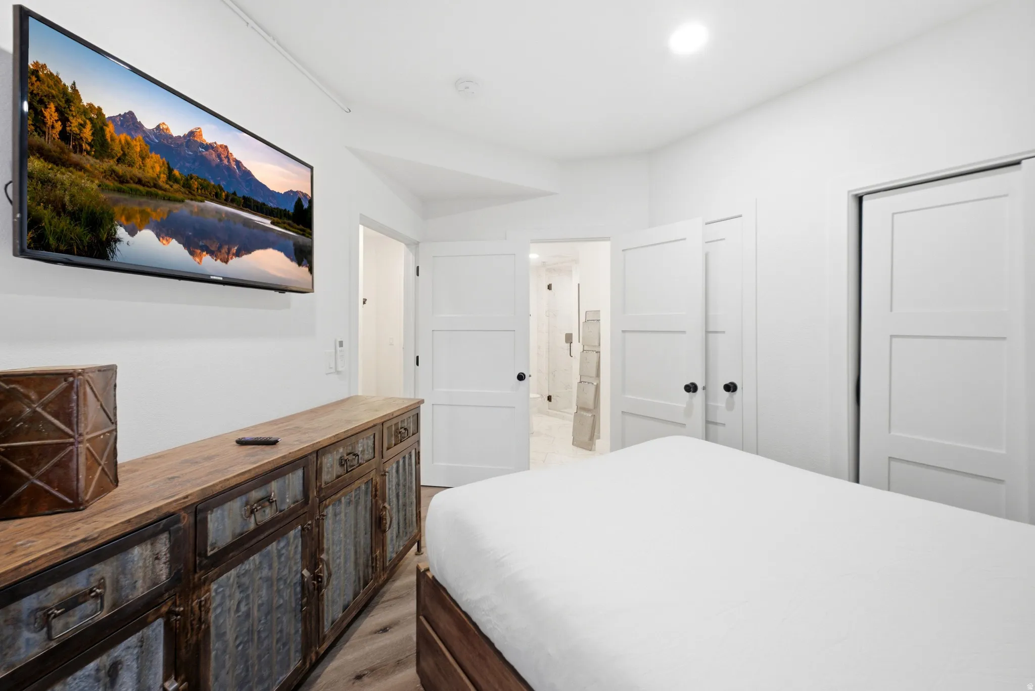 Recessed lighting, wood-finish flooring, white paneled doors, and matte black door hardware
