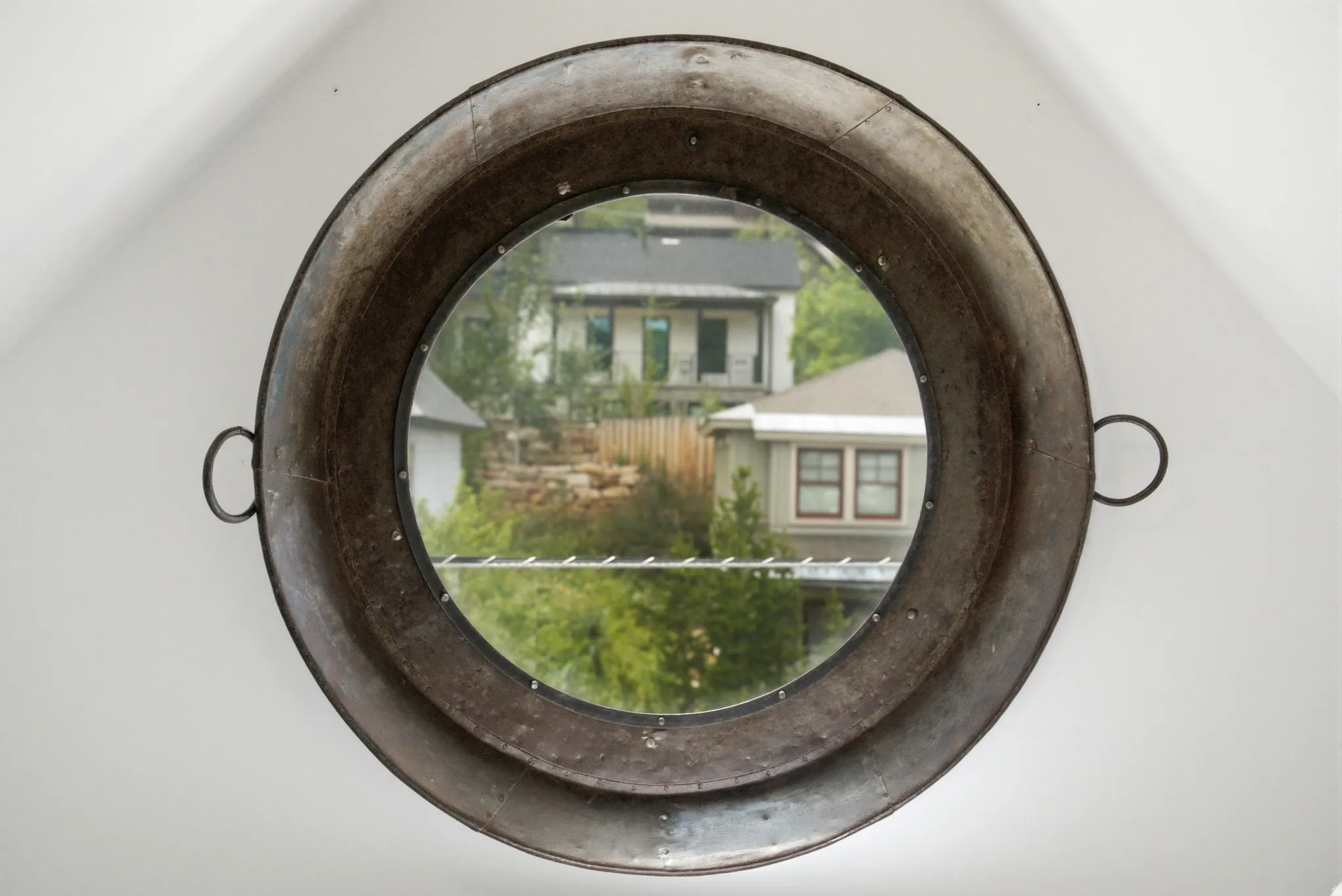 Circular window with a distressed metallic frame and riveted detailing