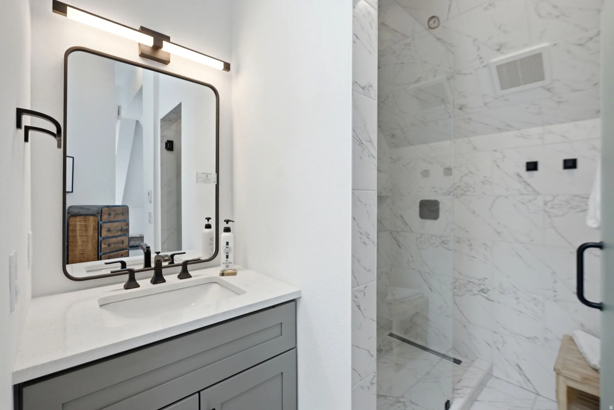 Bathroom featuring a single vanity with a gray cabinet, white countertop, and rectangular undermount sink