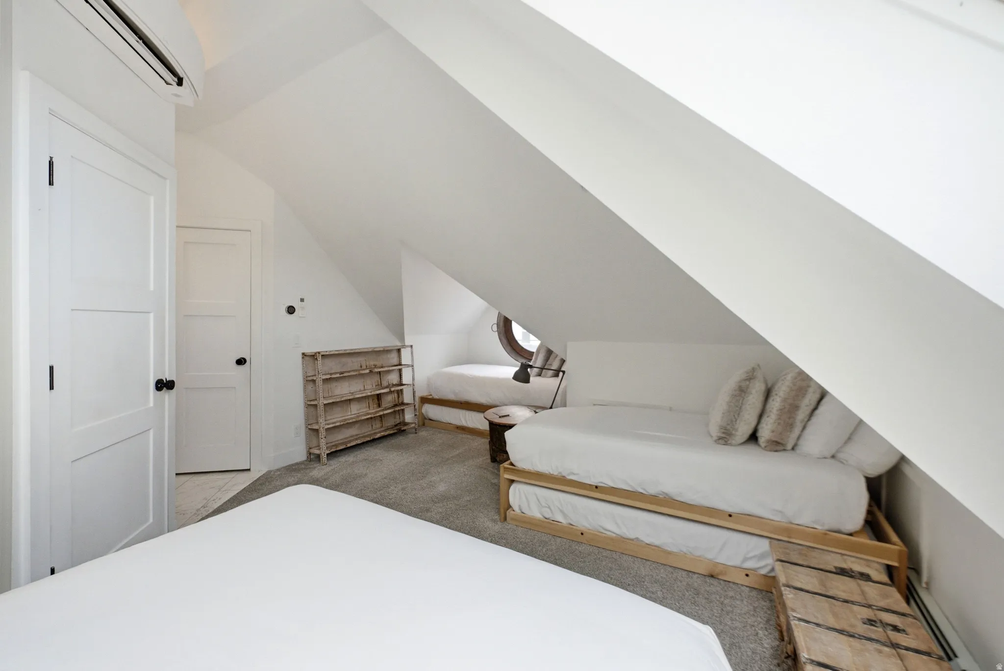 Carpeted attic space featuring sloped ceilings, white paneled doors, and a round window