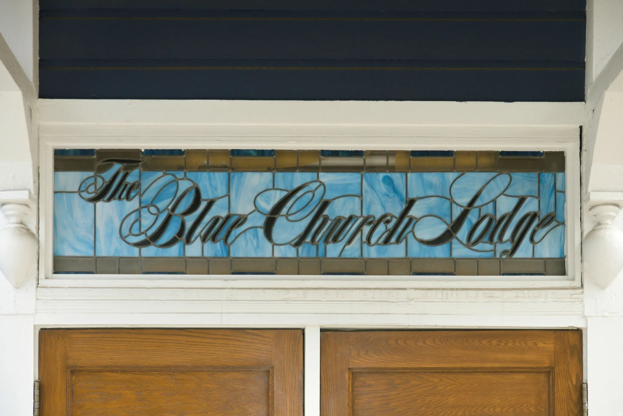 Stained glass transom window over double wood doors