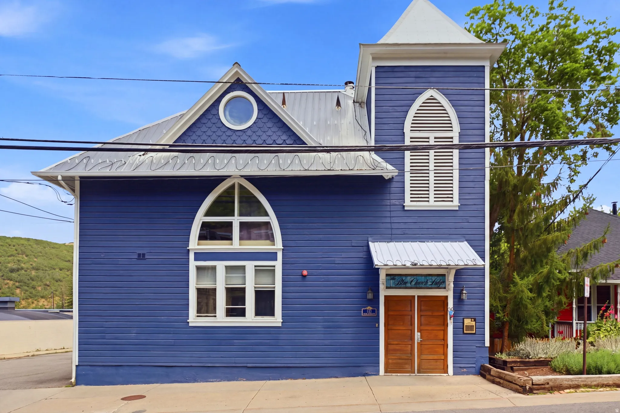 Historic-style facade featuring deep blue siding and a prominent tower with a louvered arched window