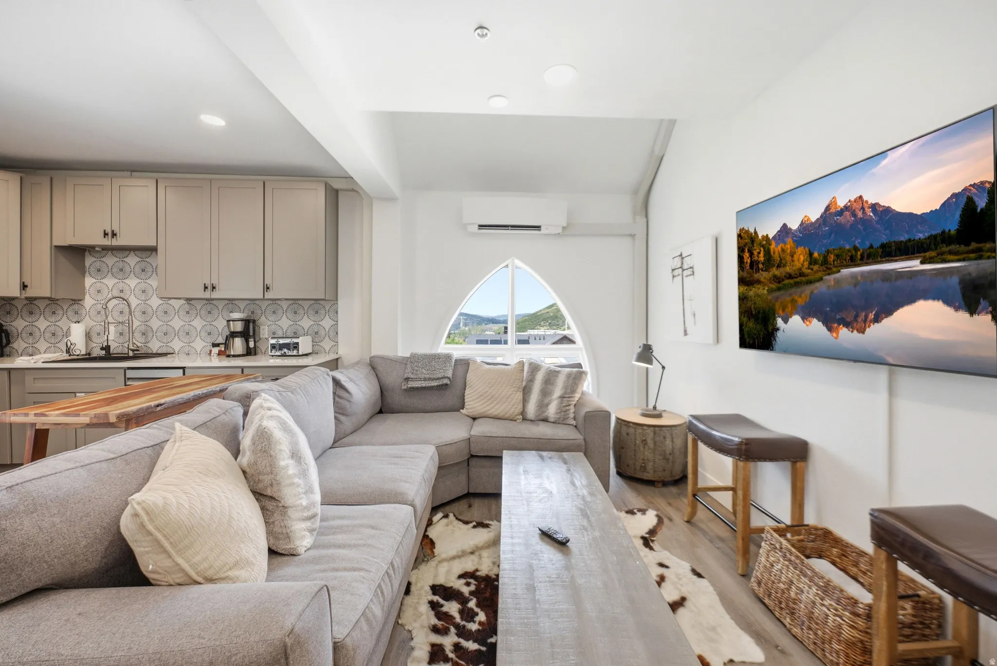 Open concept living area featuring wood-finish flooring and a distinctive arched window