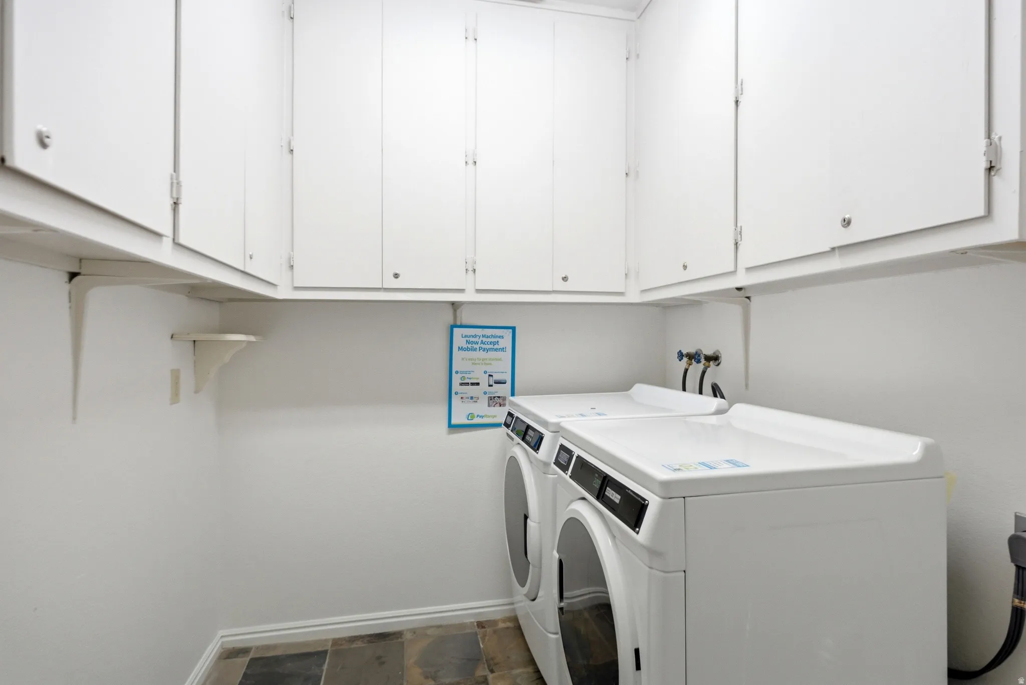 Dedicated laundry area featuring white upper cabinetry, tiled flooring, and white walls
