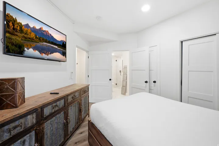 Recessed lighting, wood-finish flooring, white paneled doors, and matte black door hardware