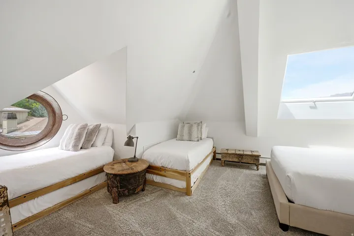 Attic space featuring vaulted ceilings, a porthole window, a large skylight, and gray patterned carpeting