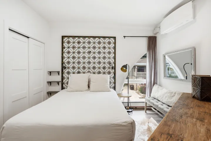 Spacious room featuring light wood-finish flooring, white walls, and a large window with courtyard visibility